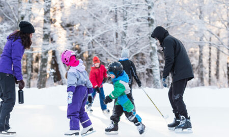 Aikuisia ja lapsia luistelemassa ulkojäällä.