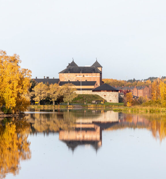 Hämeen linna edustalla järvi sekä syksyisiä puita.
