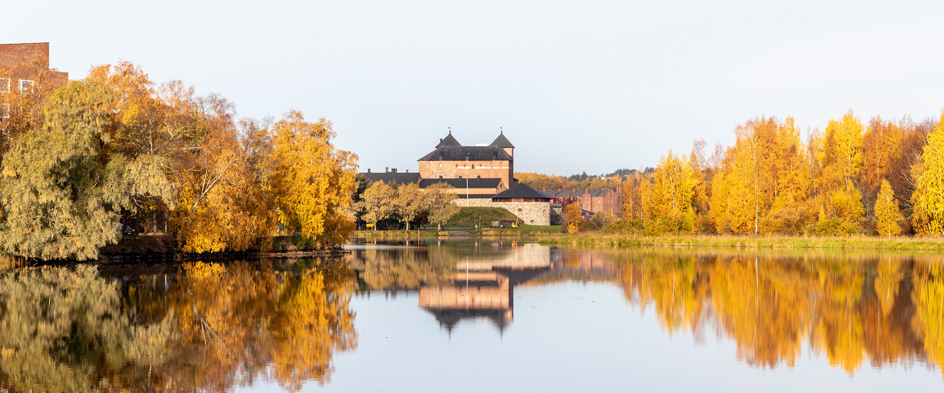 Hämeen linna edustalla järvi sekä syksyisiä puita.