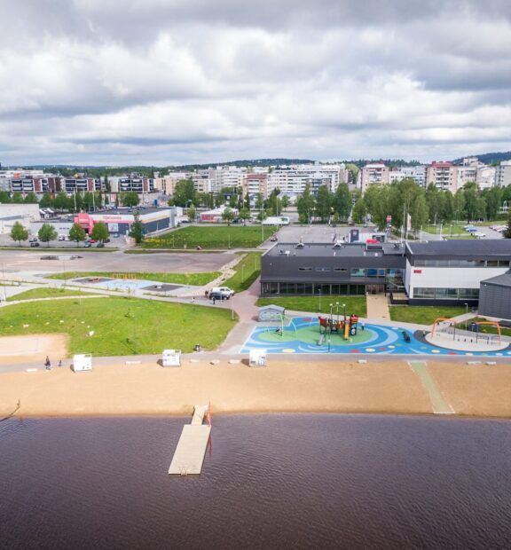 Järven rannalla olevan uimahalli, jonka edessä lasten leikkipaikka sekä uimaranta laitureineen
