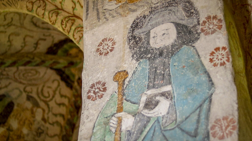 Kirkon seinässä oleva seinämaalaus, joka esittää pyhiinvaeltajaa. 