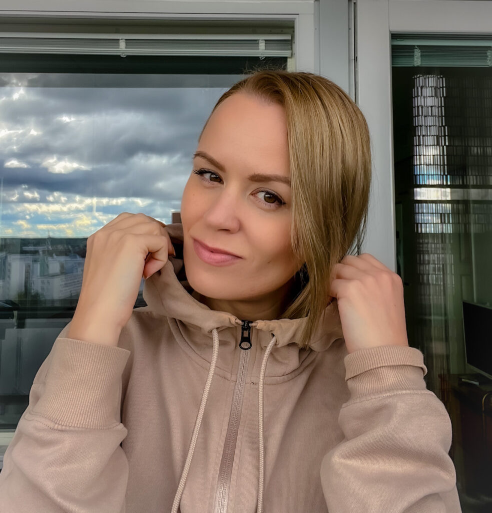 Nainen katsoo kameraan ja pitää kiinni hupparin hupusta.