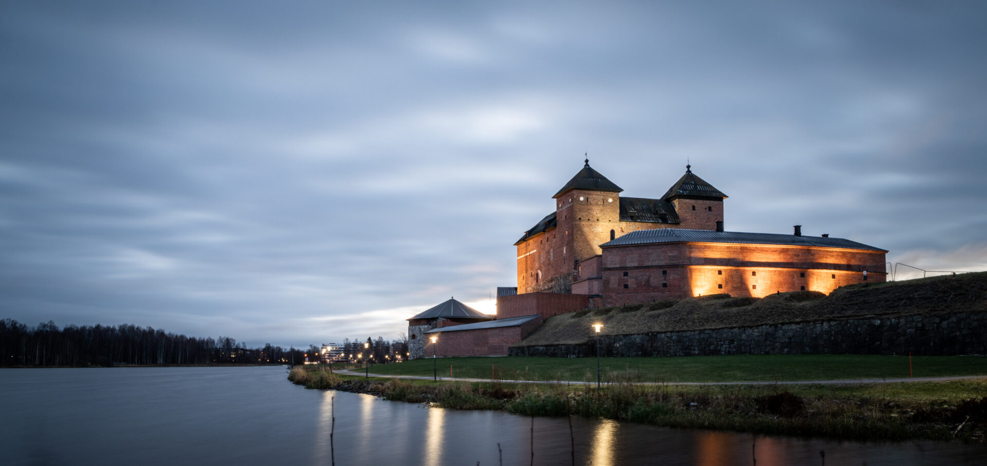 Järven rannalla sijaitseva punatiilinen vanha Hämeen linna.