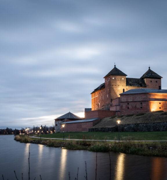 Järven rannalla sijaitseva punatiilinen vanha Hämeen linna.