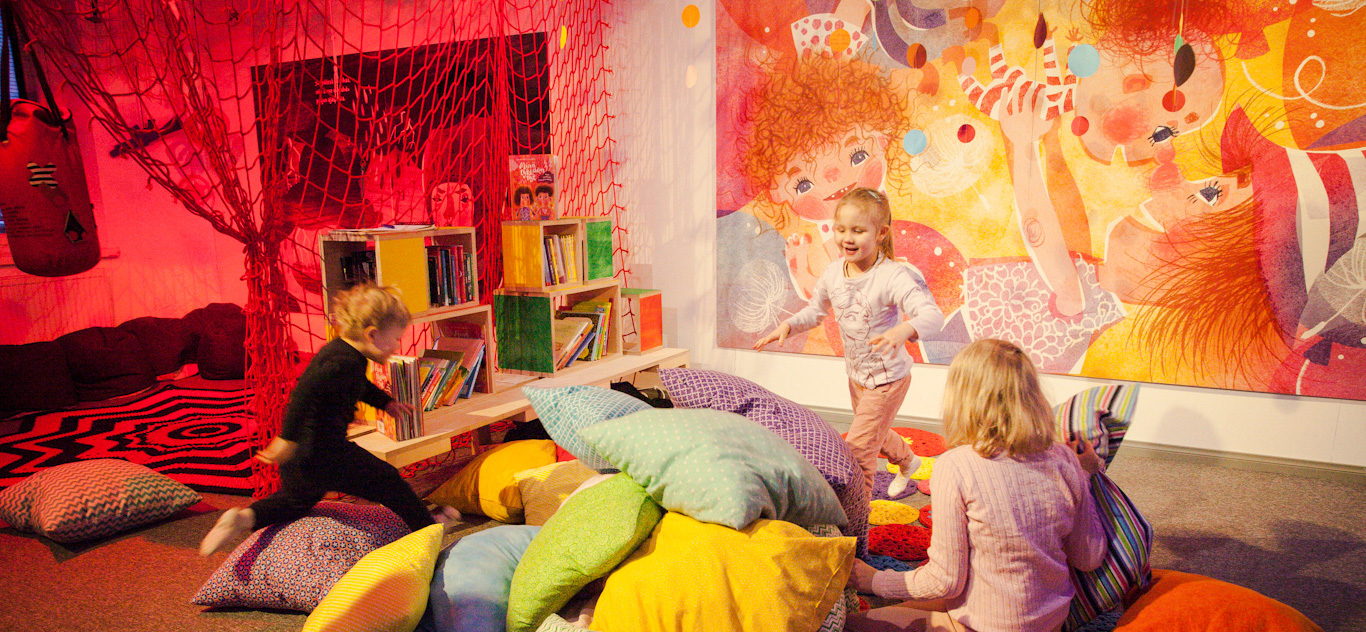 Lapset leikkivät tyynysotaa värikkäillä tyynyillä