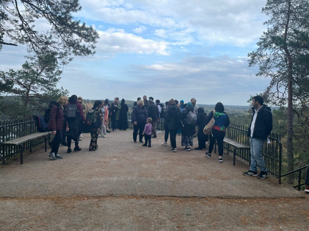 Joukko ihmisiä katsomassa kansallismaisemaa Hämeenlinnan Aulangolla
