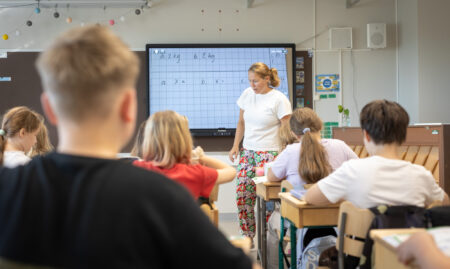 Opettaja ohjeistaa koululaisia luokassa.