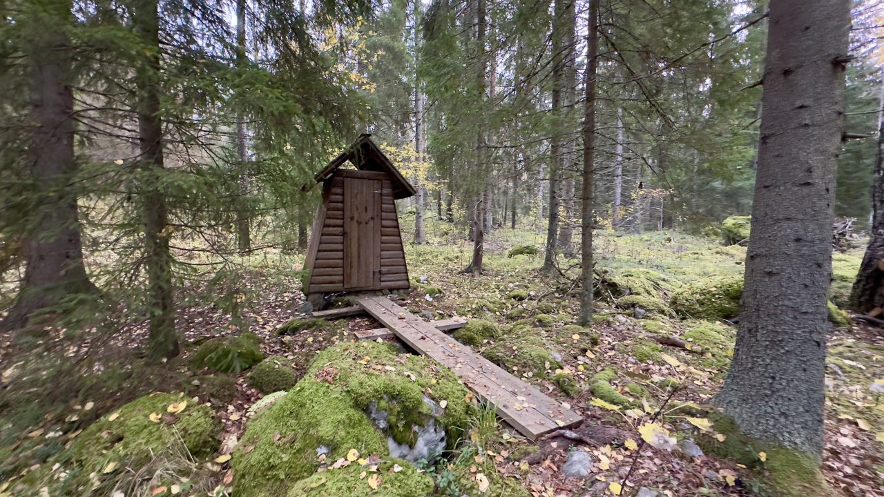 Puusta rakennettu kuivakäymälä metsässä.