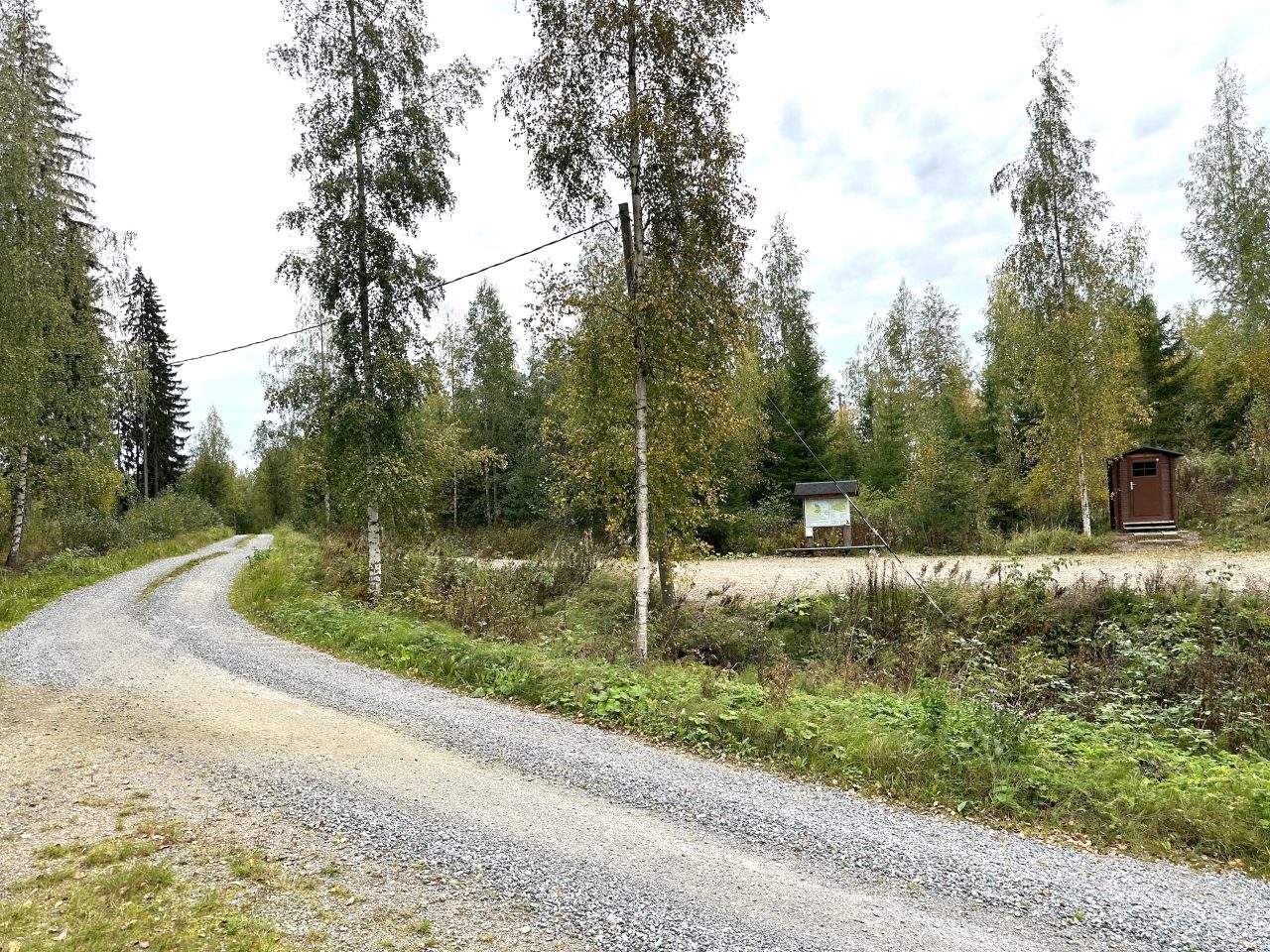 There is a gravel area next to the forest road with an information board and an outdoor toilet.