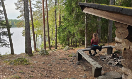 Henkilö istuu järven rannalla olevalla laavulla.