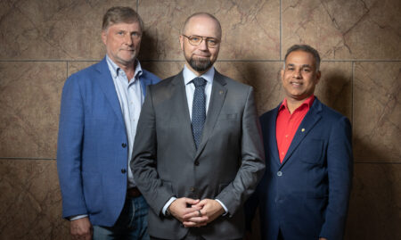 Kolme mieshenkilöä seisoo rinnakkain.