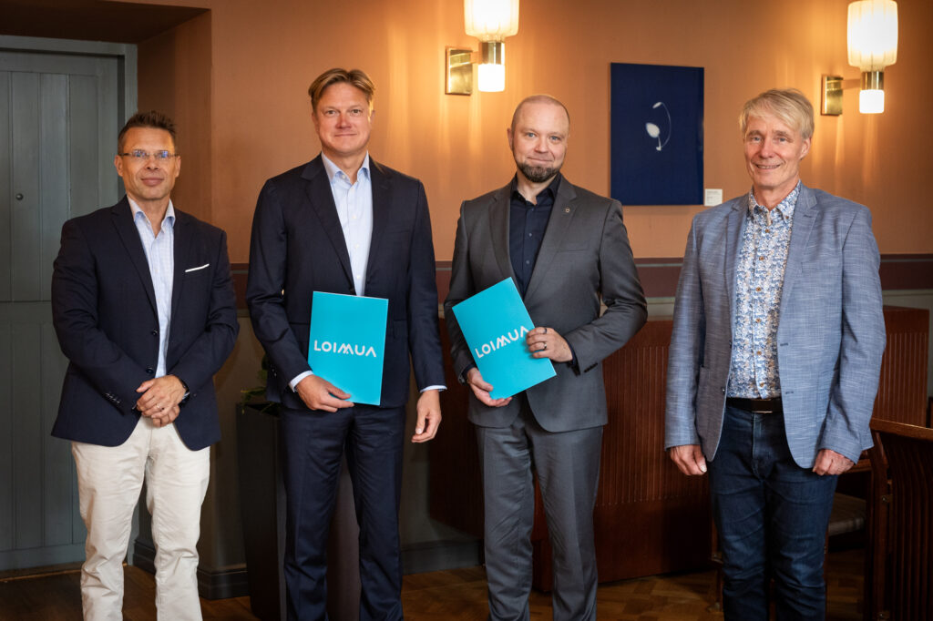 Neljä henkilöä katsoo kameraan ja hymyilee.