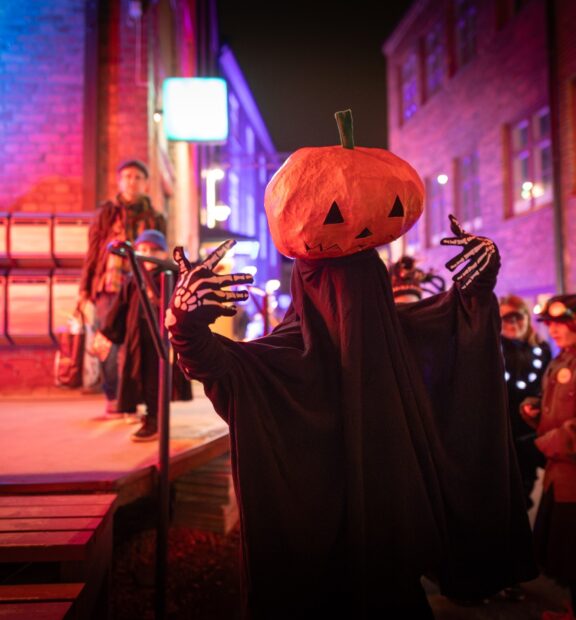 Kurpitsahahmo yleisön seassa Verkatehtaalla.