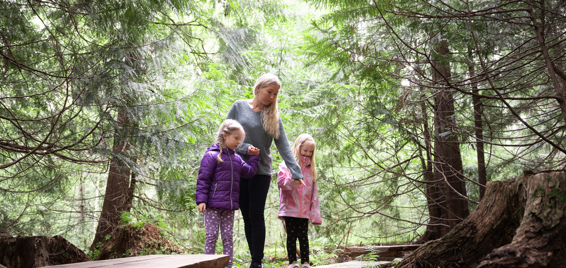 Äiti kahden lapsen kanssa Aulangon tuijametsässä.