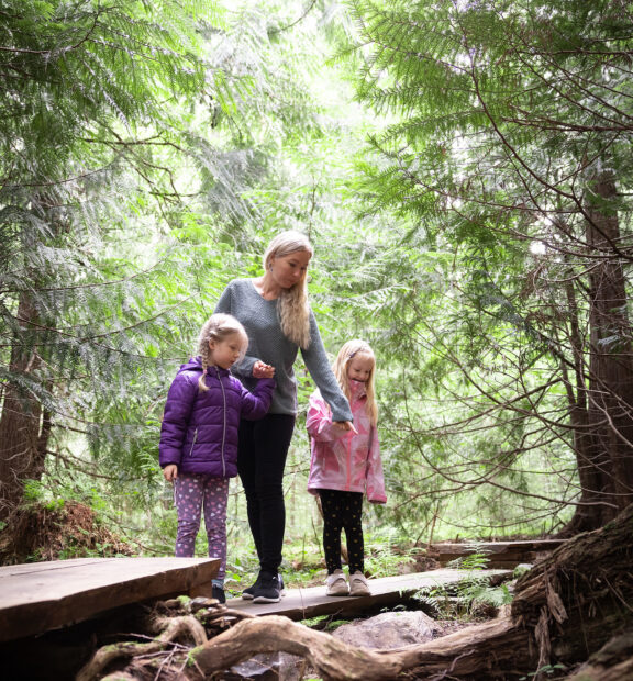 Äiti kahden lapsen kanssa Aulangon tuijametsässä.