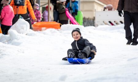 Lapsi laskee pulkkamäkeä.