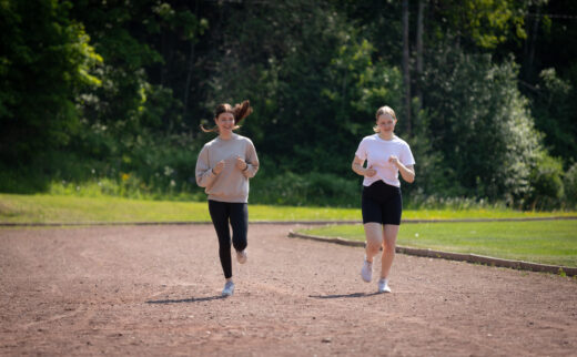 Two young people are running on a sports field.