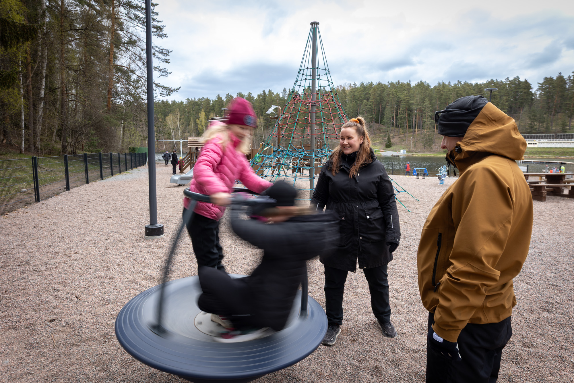 Kaksi lasta leikkivät kahden aikuisen kanssa Ahveniston leikkipaikalla.