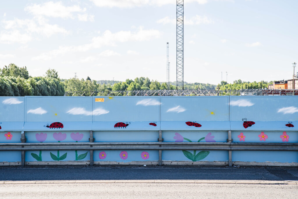 Kaide, jossa maalaus. Maalauksessa taivas, kukkia ja leppäkerttuja