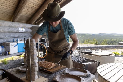 A chef preparing food in an outdoor kitchen.