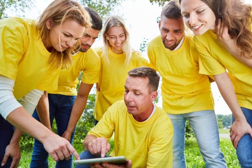 A group dressed in yellow shirts in a circle making a plan.