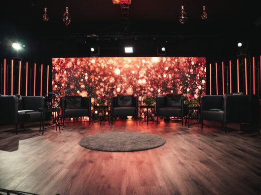 A studio with rows of chairs and a colorful red illuminated backdrop.