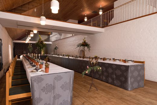 The castle hall set up for guests. Long tables arranged in a U-shape, fully laid.