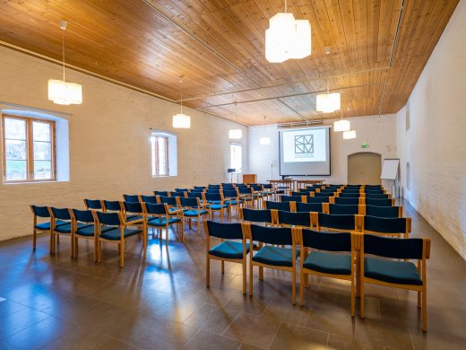 A large hall set up as a lecture room. A large whiteboard is visible on the back wall.