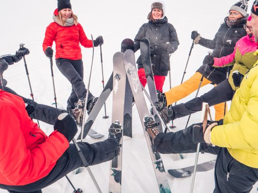 A group of people bringing the tips of their skis together in a circle in a snowy landscape.