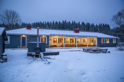 A blue winter twilight scene with a long blue building and large windows letting in light.