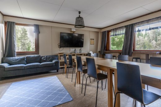 Lounge area with bar stools and sofas. A television on the back wall.