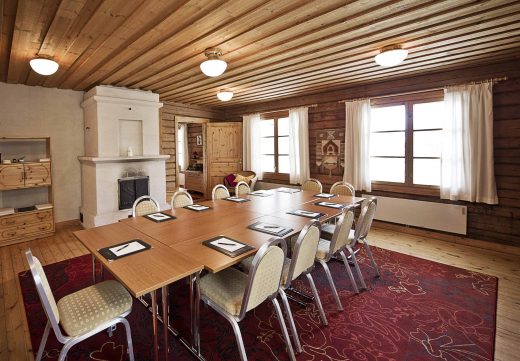 Meeting room in the Red Cottage. A group-style table set up for a meeting. An old heating stove can be seen in the background.
