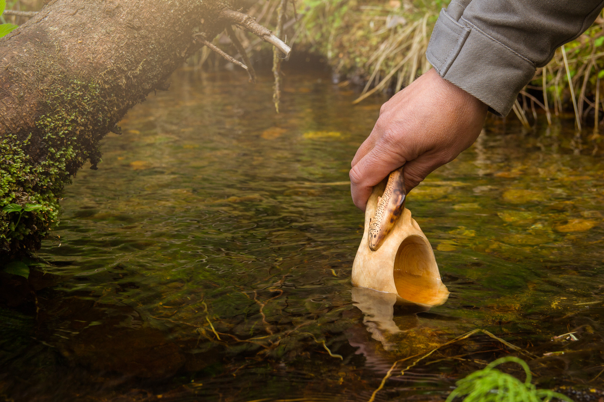 Water is scooped from a clear spring with a kuksa.