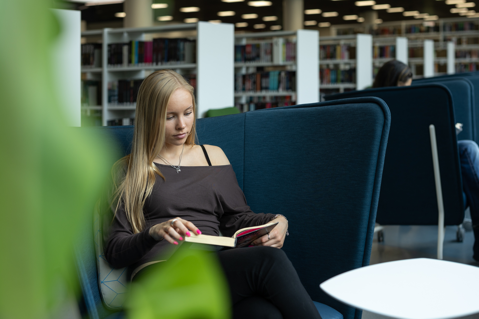 Nuori lukee kirjaa kirjastossa.