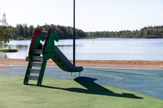 Liukumäki Hämeensaaren leikkipaikalla, taustalla näkyy uimaranta ja järveä.
