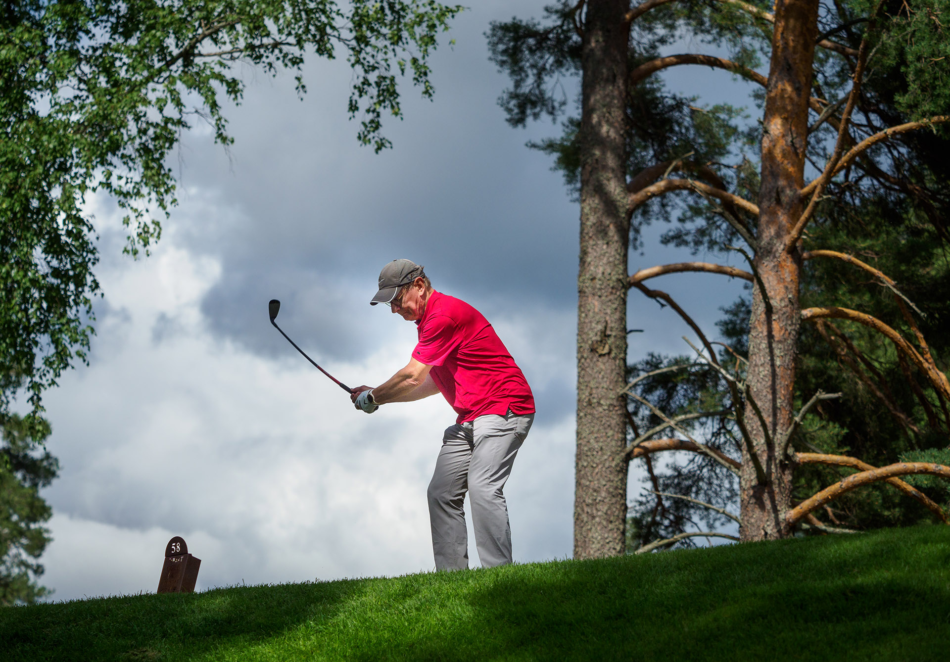 A person swinging a golf club to hit a ball.