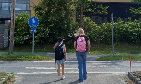 Kaksi lasta kävelemässä suojatiellä koulun edessä.