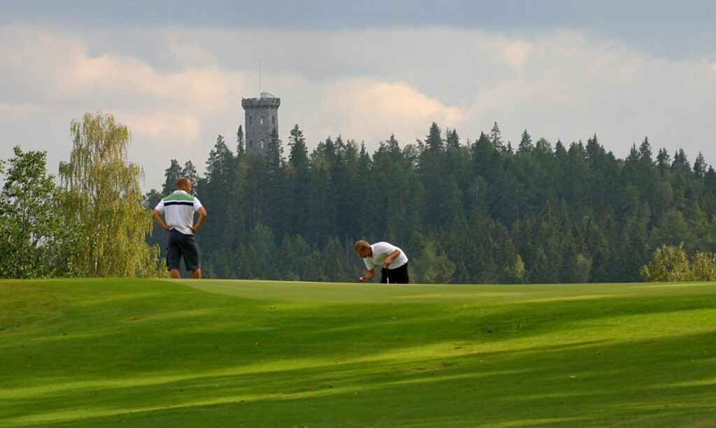 Kaksi ihmistä pelaa golfia Aulangon golfkentällä