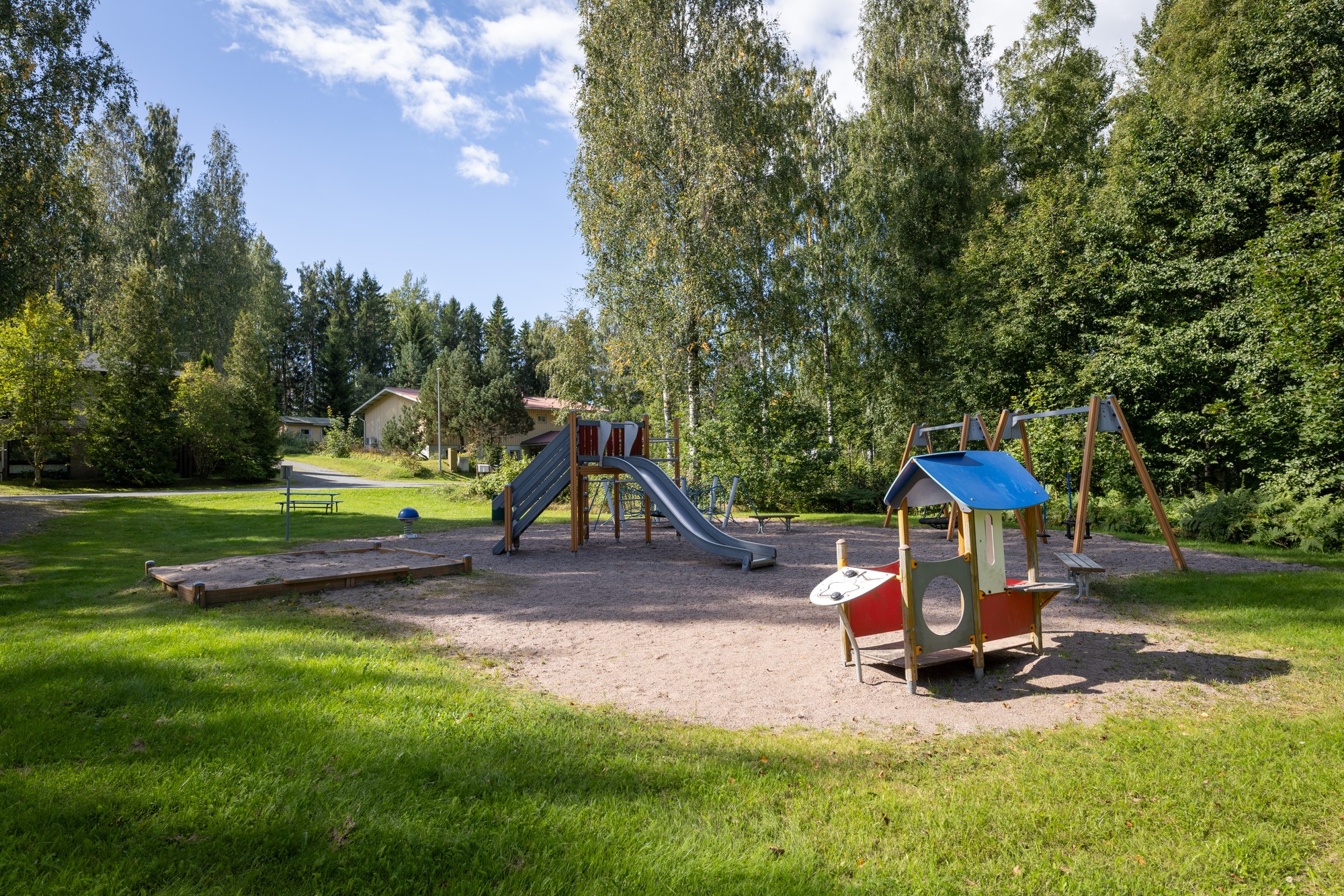 lähdepuiston leikkipaikka, jossa on muun muassa liukumäki, hiekkalaatikko ja keinuja.