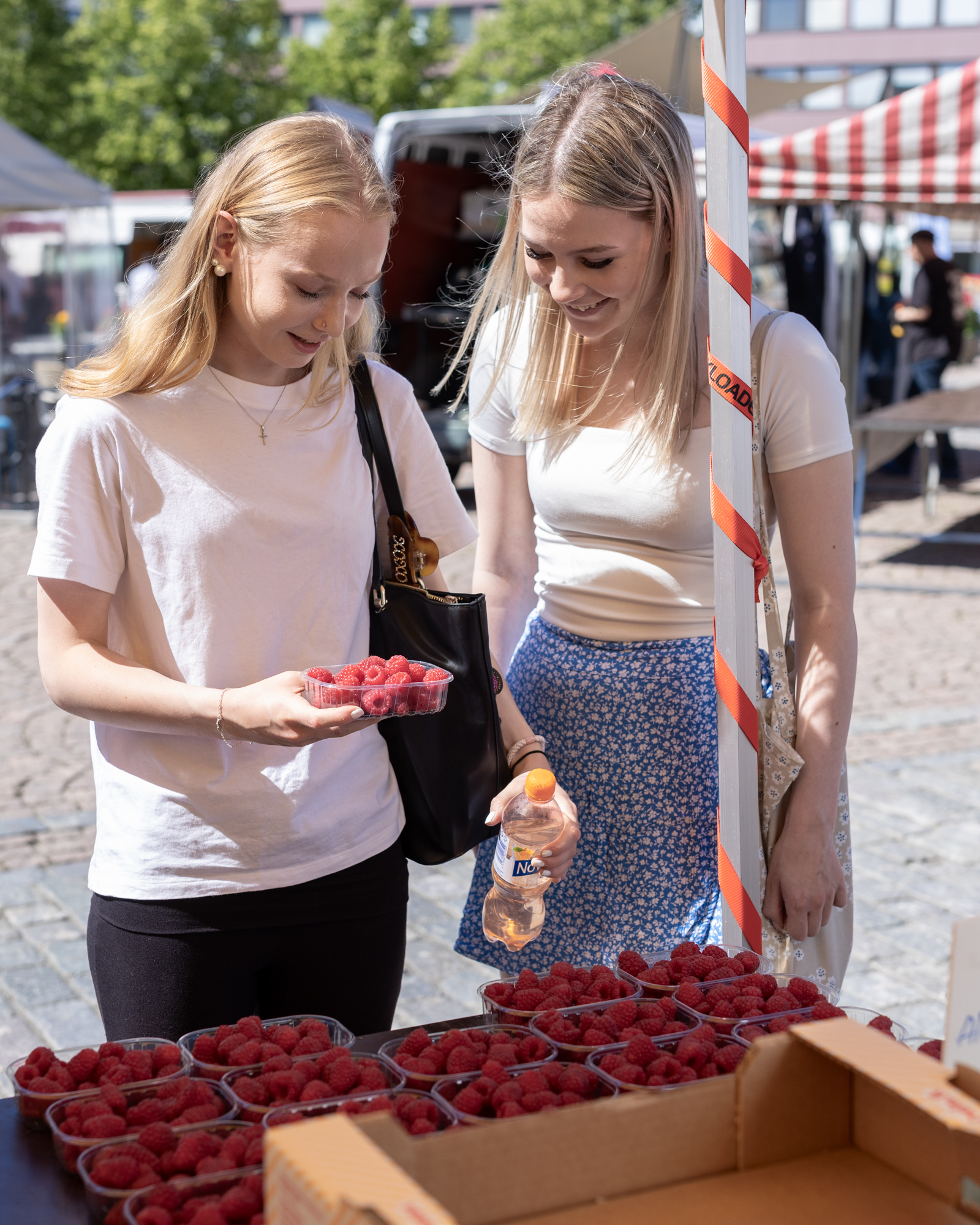 Kaksi nuorta asiakasta torikojulla vadelmarasia kädessään.