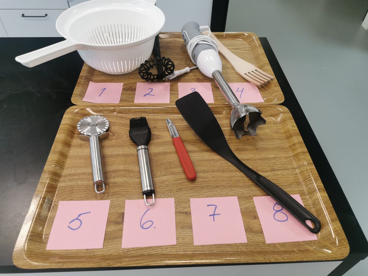 Home economics utensils lined up on trays.